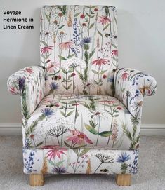 an upholstered chair with flowers and plants on the back, in front of a white wall