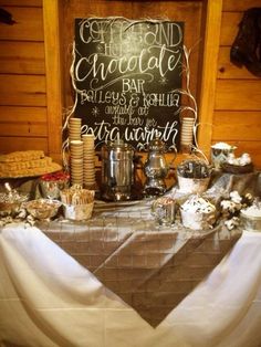 a table topped with lots of food and desserts next to a chalkboard sign