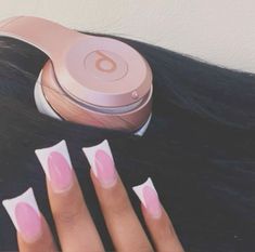 a woman's hand with pink and white manies next to headphones on top of her hair