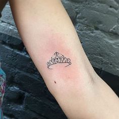 a woman with a tattoo on her arm that has a small crown on the left arm