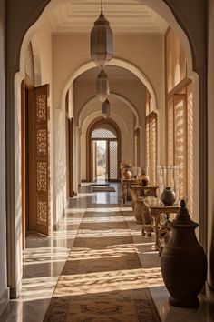 an archway leading into a hallway with vases on either side and lamps hanging from the ceiling