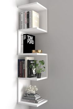 three white shelves with books and plants on them