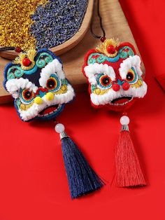 two chinese style ornaments with tassels are on a red surface next to other decorations