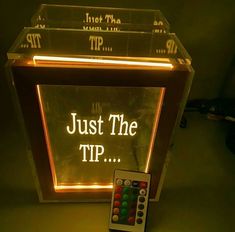 a remote control sitting in front of a light box with just the tip written on it