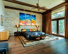 a bedroom with wood floors and paintings on the wall above the bed, along with two couches