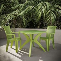 a green table and two chairs in front of some plants