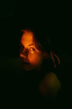 a woman in the dark with her eyes open and looking off into the distance at night