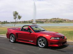 a red sports car is parked on the side of the road in front of a fountain