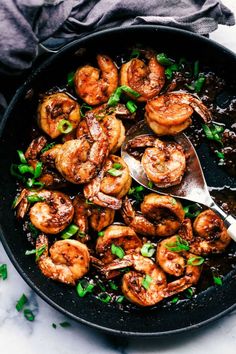 a skillet filled with cooked shrimp and garnished with parsley on the side