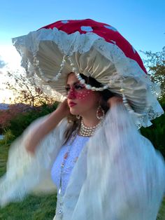 a woman wearing a white dress and red hat with feathers on it's head