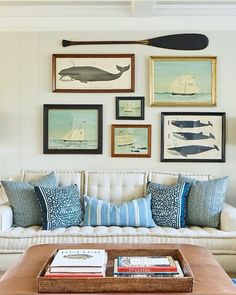 a living room filled with furniture and framed pictures on the wall above it's coffee table