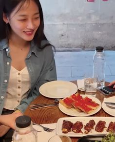 a woman sitting at a table with plates of food