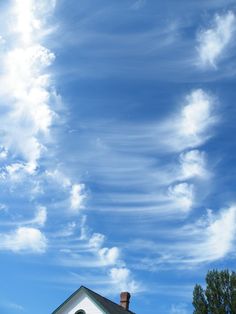 a white house sitting under a blue sky with wispy clouds in the background