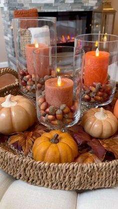 candles and pumpkins are arranged in a basket on a table with other autumn decorations