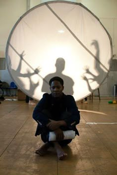 a man sitting on the floor in front of a large white object with long legs