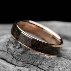 a wedding band made out of wood on top of a rock