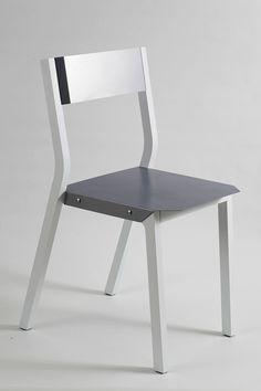 a white and black chair sitting on top of a gray floor next to a wall