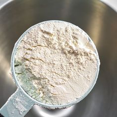 a metal bowl filled with flour on top of a table