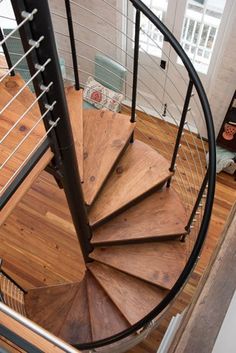 a spiral staircase in a home with wood floors and metal handrails that lead up to the second floor