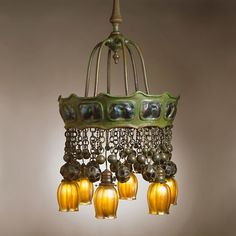 a chandelier hanging from the ceiling with five lights attached to it and several bells on each side