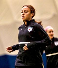 the woman is playing soccer with her team mates on the field in preparation for their next match