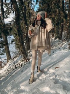 a woman standing in the snow with her arms around her head and wearing white tights