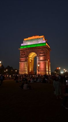 people sitting on the ground in front of an illuminated arch