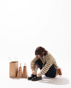 a woman sitting on the ground with her shoes in front of her and bags behind her