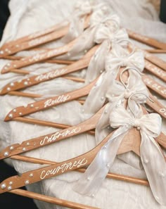 wooden clothes hangers with names on them and ribbons tied to them, sitting on a table