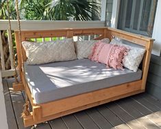 a wooden porch swing with pillows on it