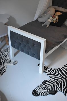 a zebra rug is laying on the floor next to a bed with a gray headboard