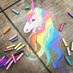 chalk crayons are scattered around a drawing of a unicorn