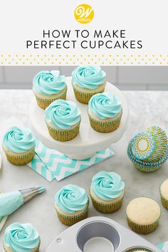 cupcakes with blue frosting sitting on top of a counter next to a cake pan