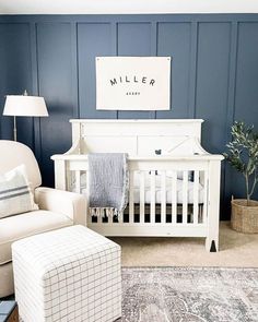 a baby's room with blue walls and white furniture, including a crib