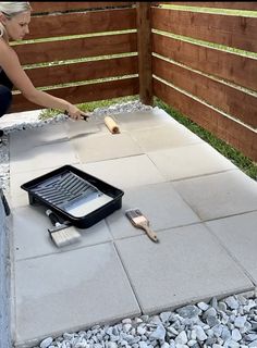 a woman is painting the outside of her house with paintbrushes and a spatula