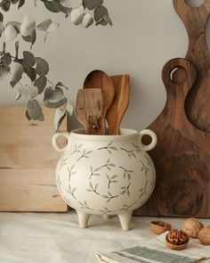 a white vase sitting on top of a table next to wooden spoons