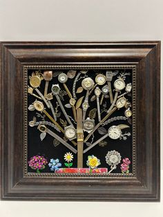 a wooden frame with a tree made out of clocks and flowers on the inside, in front of a white wall