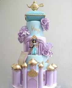 a three tiered cake with princess figurines on top and purple flowers around the edges