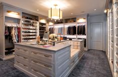 a walk in closet filled with lots of drawers and clothes hanging on the wall next to a counter