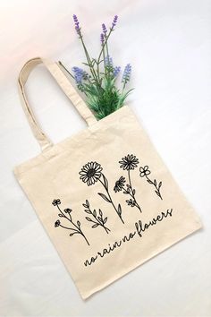 a tote bag with flowers on it and the words nature never written in black ink