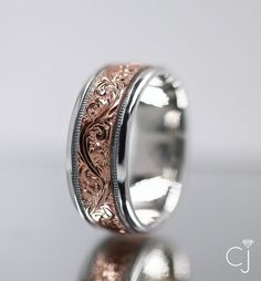 a wedding ring with an intricate design on the outside and inside, sitting on a reflective surface