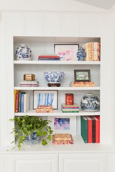 a white book shelf with books and vases on it