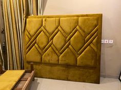 a yellow headboard sitting on top of a bed next to a wooden table and chair