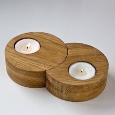 two wooden candle holders sitting on top of each other with white candles in the middle