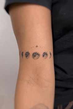 a woman's arm with phases of the moon and stars on her left side