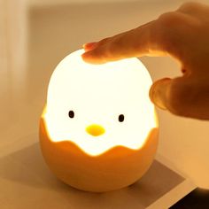 a person touching an orange with a light on it's face and the head of a chicken