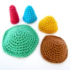 three crocheted hats sitting next to each other on top of a white surface