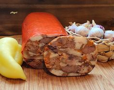 some food is laying out on a wooden surface next to garlic and peppers, along with an orange pepper