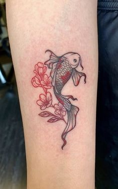 a fish tattoo on the leg with red flowers and leaves around its body, it looks like there is something in the water