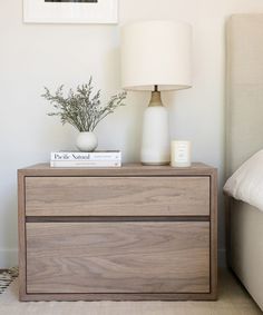 a nightstand with a book and vase on it